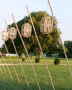 several birdcages are lined up in the grass near each other, with trees in the background