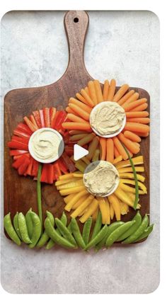 a wooden cutting board topped with vegetables and dips