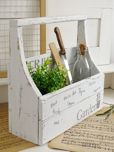 an old wooden crate with herbs and gardening utensils in it sitting on a table