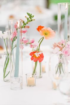 several vases with flowers and candles on a table