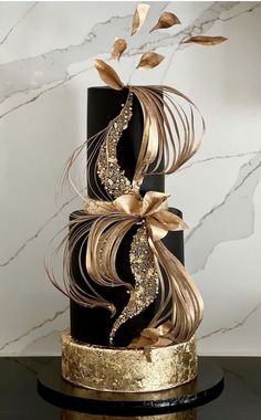 a black and gold wedding cake with swirls on it's tiered base