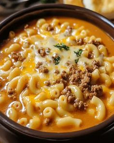 a close up of a bowl of soup with cheese and meat in it on a table