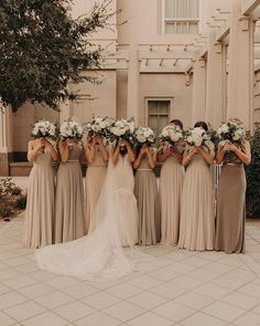 a group of women standing next to each other in front of a building with flowers on their heads