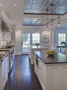 a large kitchen with white cabinets and wood flooring, along with an island in the middle