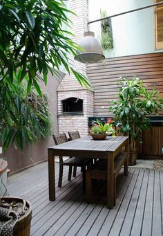 an outdoor dining area with potted plants on the deck and a fire place in the background