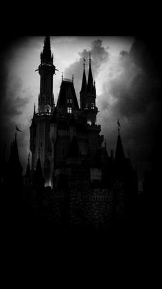 the castle is lit up in black and white, with dark clouds behind it at night