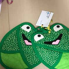 two green frog oven mitts hanging on the wall next to a pair of scissors