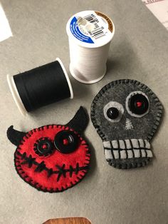 two decorated items sitting on top of a table next to spools of thread