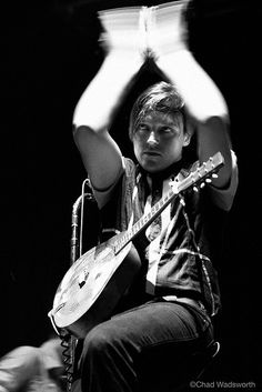 black and white photograph of a man playing an acoustic guitar with his hands in the air