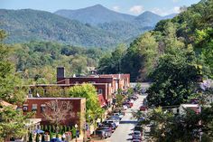 cars are parked on the street in front of some buildings and trees with mountains in the background