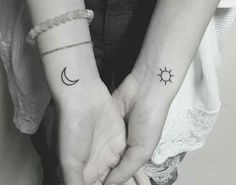 two people holding hands with small tattoos on their wrist and the sun and moon tattoo