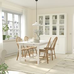 a white dining room table and chairs in front of a window with lots of windows