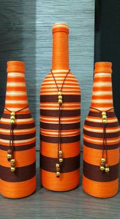 three orange and brown striped vases sitting next to each other on top of a table