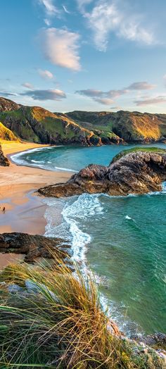 the beach is surrounded by green hills and blue water