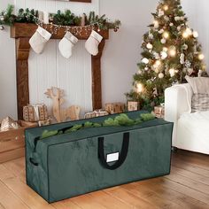 a christmas tree in a living room with stockings on the fireplace and presents under it