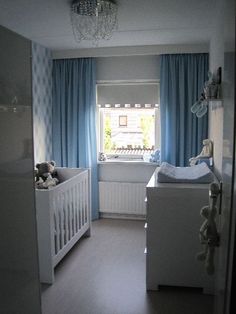 a baby's room with blue curtains and white furniture