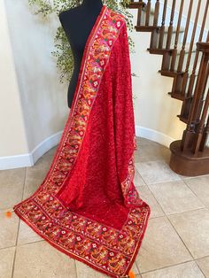 This stunning Fulkari piece features a mesmerizing blend of geometric patterns, blooming florals, and intricate motifs, brought to life with vibrant threads. The meticulous stitching and attention to detail make this piece a true work of art, showcasing the skill and craftsmanship behind Fulkari embroidery. Red Embroidered Dupatta Shawl, Red Embroidered Shawl Dupatta, Festive Multicolor Traditional Wear With Intricate Embroidery, Festive Multicolor Traditional Wear With Embroidery, Festive Jamawar Dupatta With Intricate Embroidery, Traditional Multicolor Embroidered Lehenga, Chinon Traditional Wear With Intricate Embroidery For Navratri, Traditional Dupatta With Intricate Embroidery, Red Shawl With Intricate Embroidery In Traditional Drape