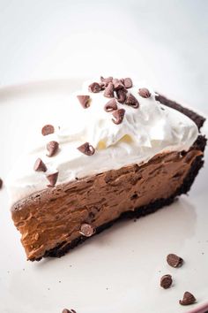 a piece of chocolate pie with whipped cream and chocolate chips on top, sitting on a white plate