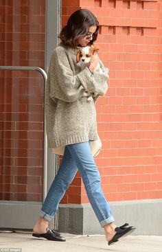 a woman is walking down the street with her dog