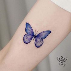 a small blue butterfly tattoo on the right arm and lower leg, with an insect sitting on it's side