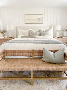 a large bed sitting next to a wooden bench in a bedroom