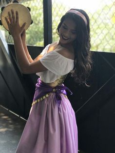 a woman in a purple and white dress holding a drum