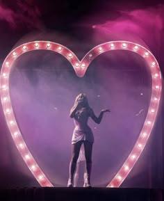 a woman standing in front of a heart shaped light