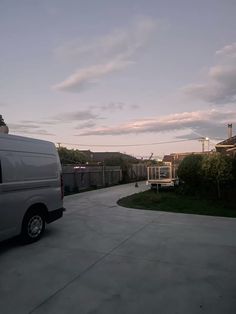 a white van parked in a driveway next to a house and fenced in area