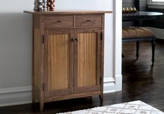 a wooden cabinet sitting on top of a hard wood floor next to a white wall