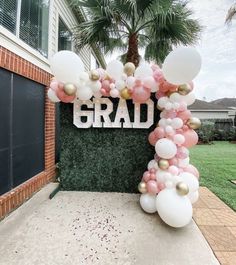 a balloon arch with the word grad spelled out in gold and white balloons on it