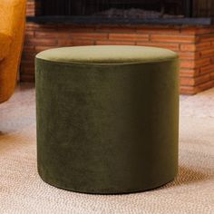 a green ottoman sitting in front of a fireplace