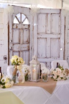 the table is set up with flowers and candles for an outdoor wedding reception in front of old doors