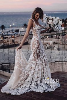 a woman standing on top of a wooden deck next to the ocean wearing a white dress