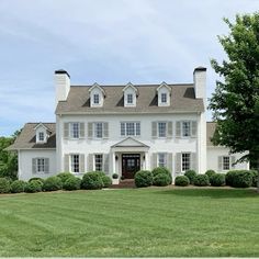 a large white house sitting on top of a lush green field