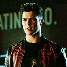 a young man in a leather jacket looking at the camera