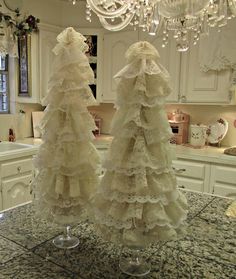 two wedding dresses are on display in a kitchen with chandelier and counter top