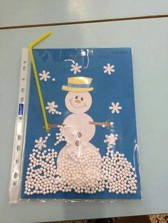 a snowman made out of white beads on a blue background with a yellow straw