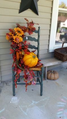 a chair with fall decorations on it sitting in front of a house