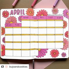 an open planner with flowers on it next to some markers and pencils in the background