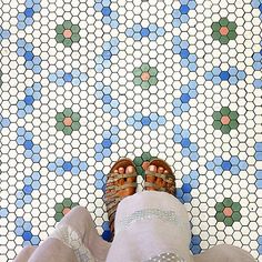 a person with sandals on their feet standing in front of a colorful tile floor that has hexagonal tiles