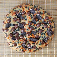 a cookie covered in chocolate chips and sprinkles on top of a cooling rack