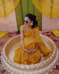 a woman in a yellow dress is sitting on a round object