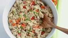 a white bowl filled with tuna salad and a wooden spoon in the bowl next to it