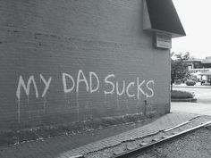 graffiti on the side of a building that says my dad sucks