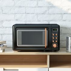 a black microwave oven sitting on top of a wooden table next to a stack of books