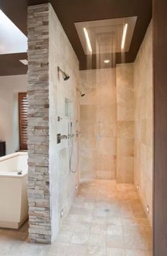 a walk in shower sitting next to a white bath tub under a skylight on top of a tiled floor