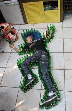 a man laying on top of green bottles in the middle of a tiled floor with his arms and legs spread out