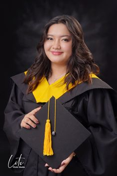 a woman wearing a graduation cap and gown posing for a photo in front of a black background