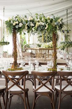 the tables are set up with white flowers and greenery on them for an elegant wedding reception