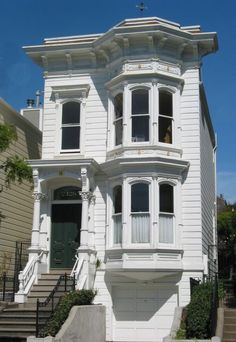 a white two story house with stairs leading up to the front door and second floor